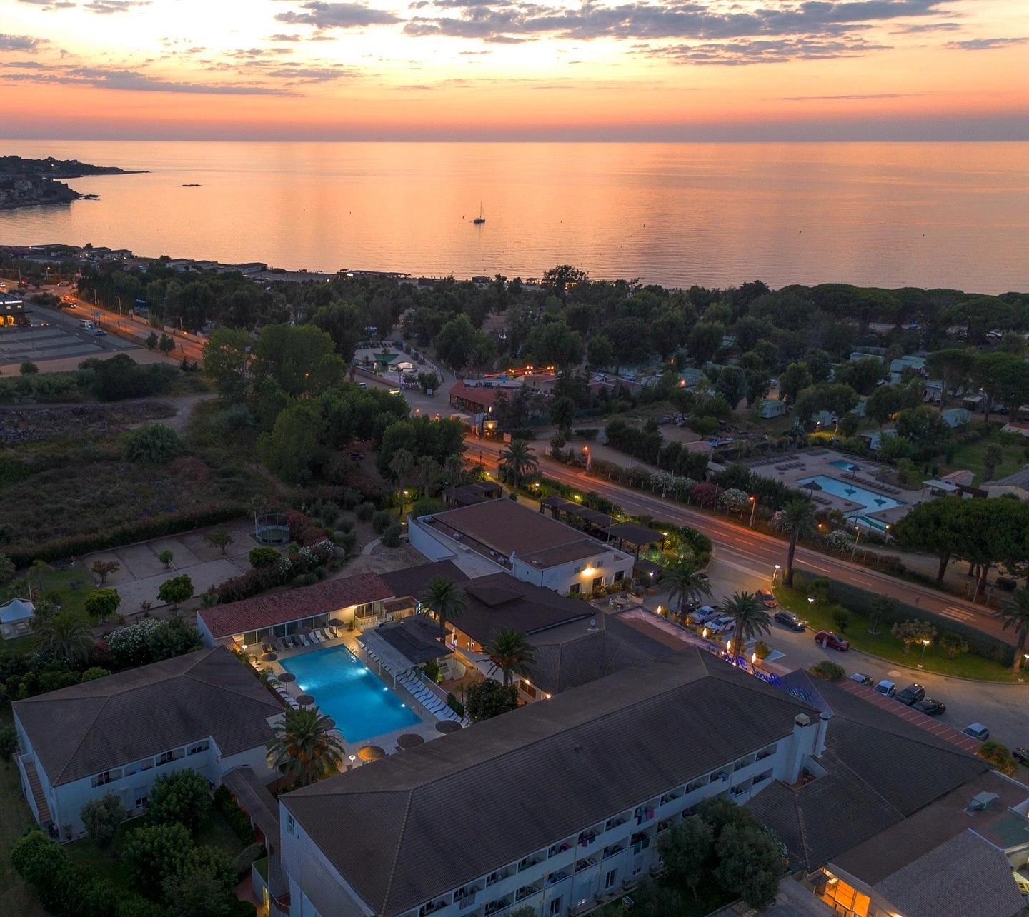 Vue au coucher du soleil sur la piscine et les bâtiments de l'hôtel Pascal Paoli 